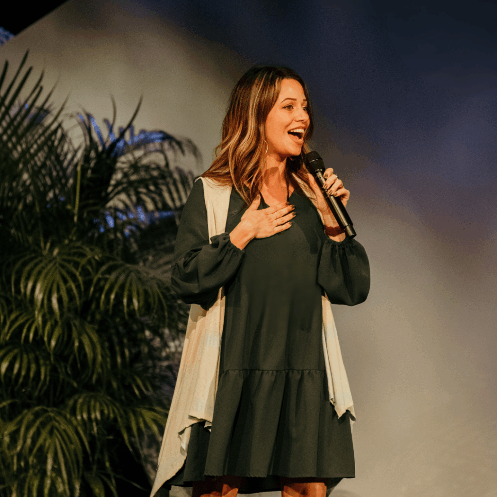 woman standing on stage speaking at an event